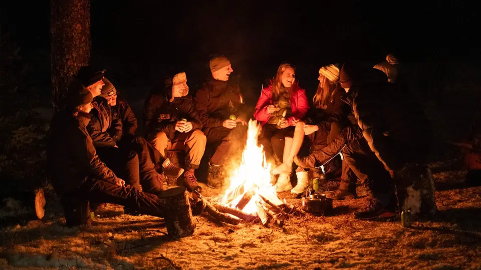 En gruppe samlet rundt et bål i skogen